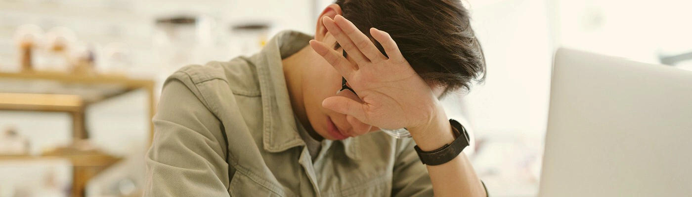 A frustrated business owner at a desk covered in paperwork